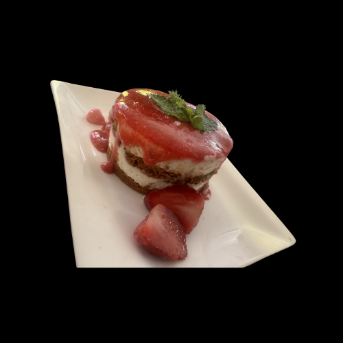 Ein herzförmiges Dessert mit roter Soße und einem Minzezweig, serviert auf einem weißen Teller mit geschnittenen Erdbeeren daneben, vor einem schwarzen Hintergrund.